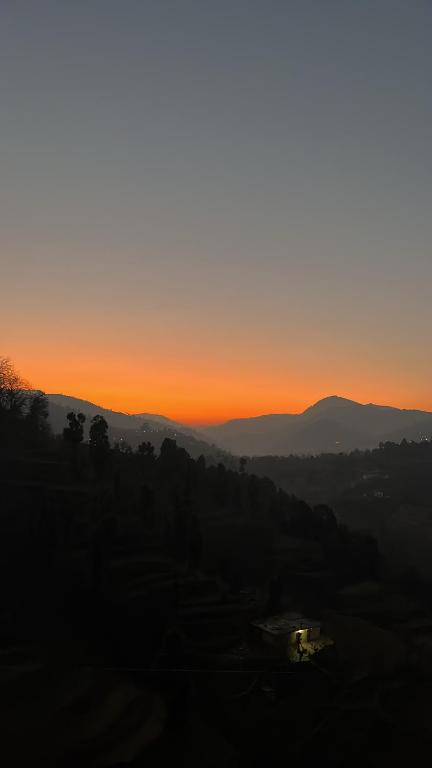 a sunset in the mountains with the sun setting at Bhimtaal cottages in Bhīm Tāl