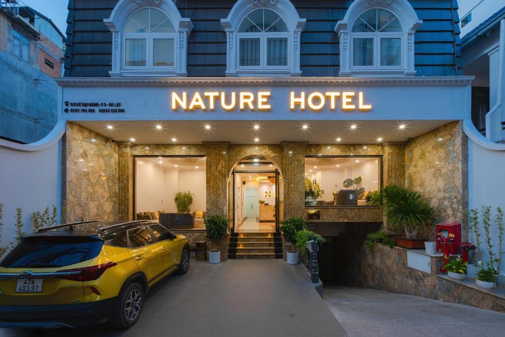 a yellow car parked in front of a nature hotel at Nature Hotel Da Lat - Le Dai Hanh in Da Lat