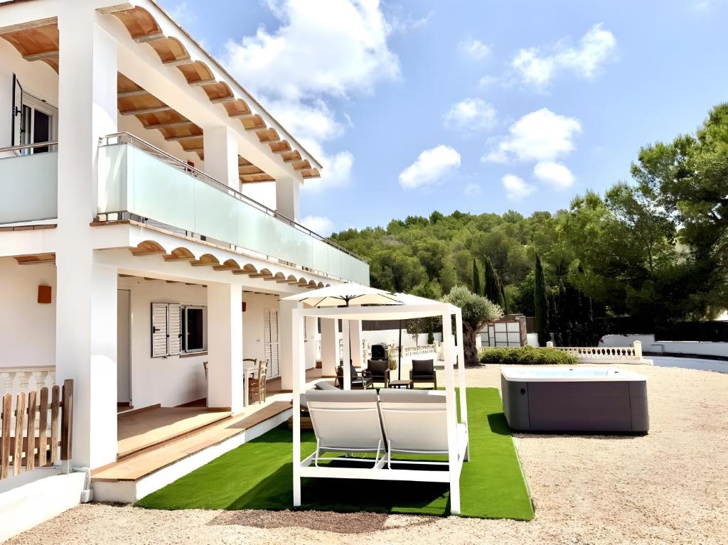 a white house with a patio with a green lawn at Villa Can Alaya in Santa Eularia des Riu