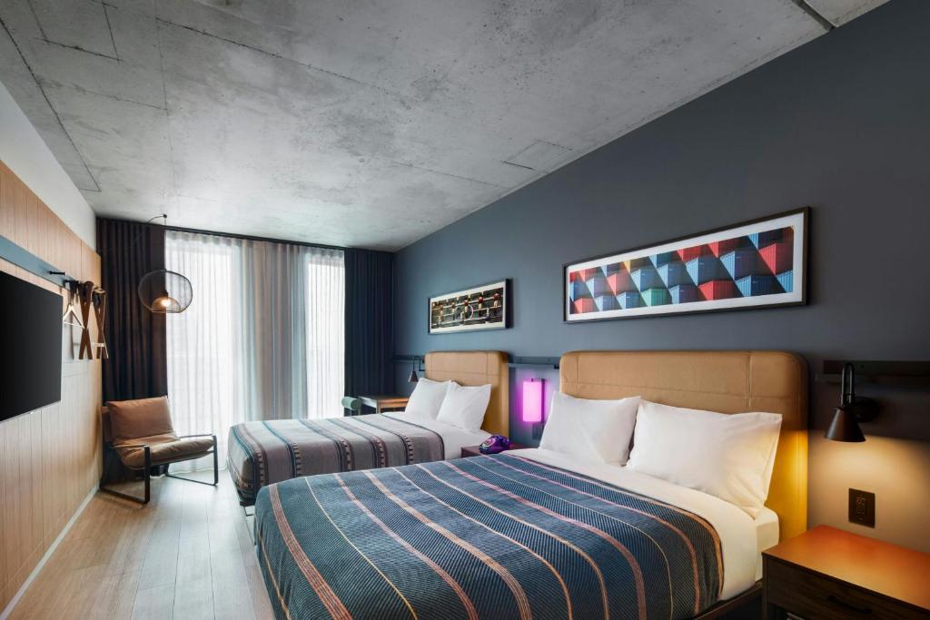 a hotel room with two beds and a chair at New Moxy Ottawa Downtown in Ottawa