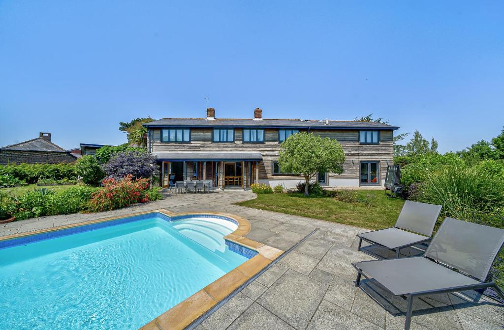 a house with a swimming pool and two chairs at Cedar Barn in Chichester