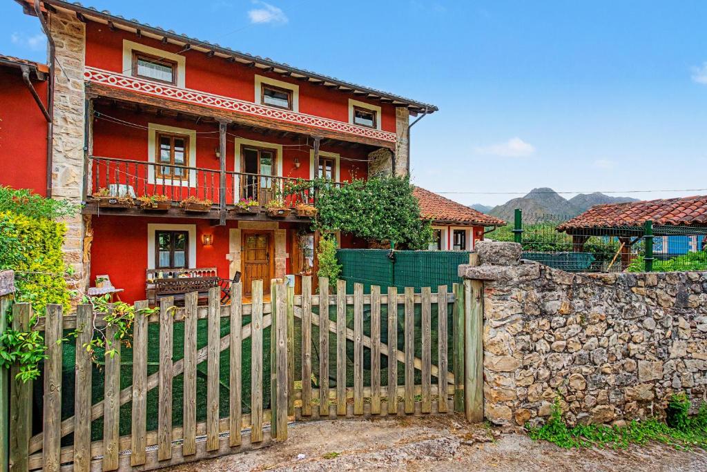 a red house with a fence and a stone wall at Casa Del Tesoro in Triongo