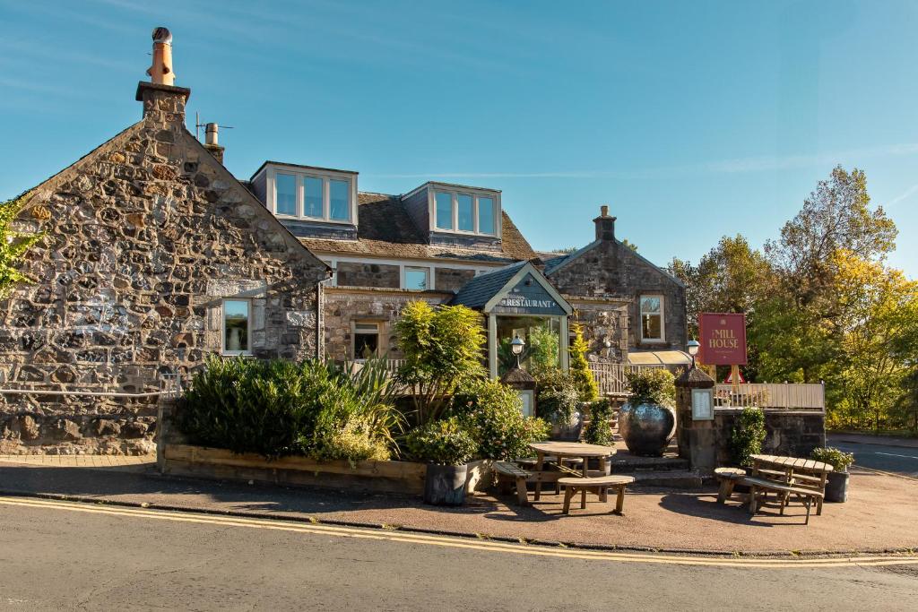 an old stone building with benches in front of it at The Mill House in Stewarton