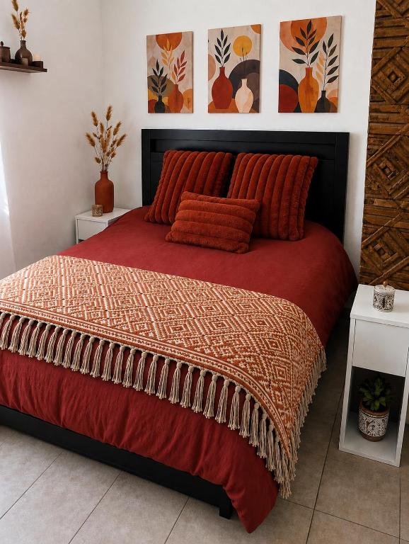 a bedroom with a large bed with a red comforter at La Dune Bohème chic in Saint-Maurice-de-Beynost
