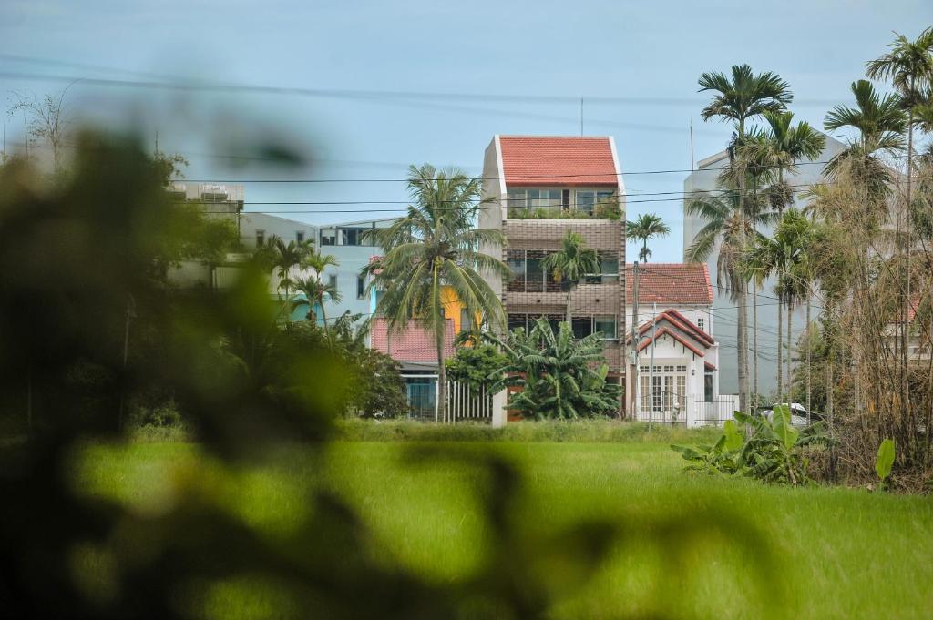 a group of buildings with palm trees in the background at Camfusion Hoi An in Hoi An