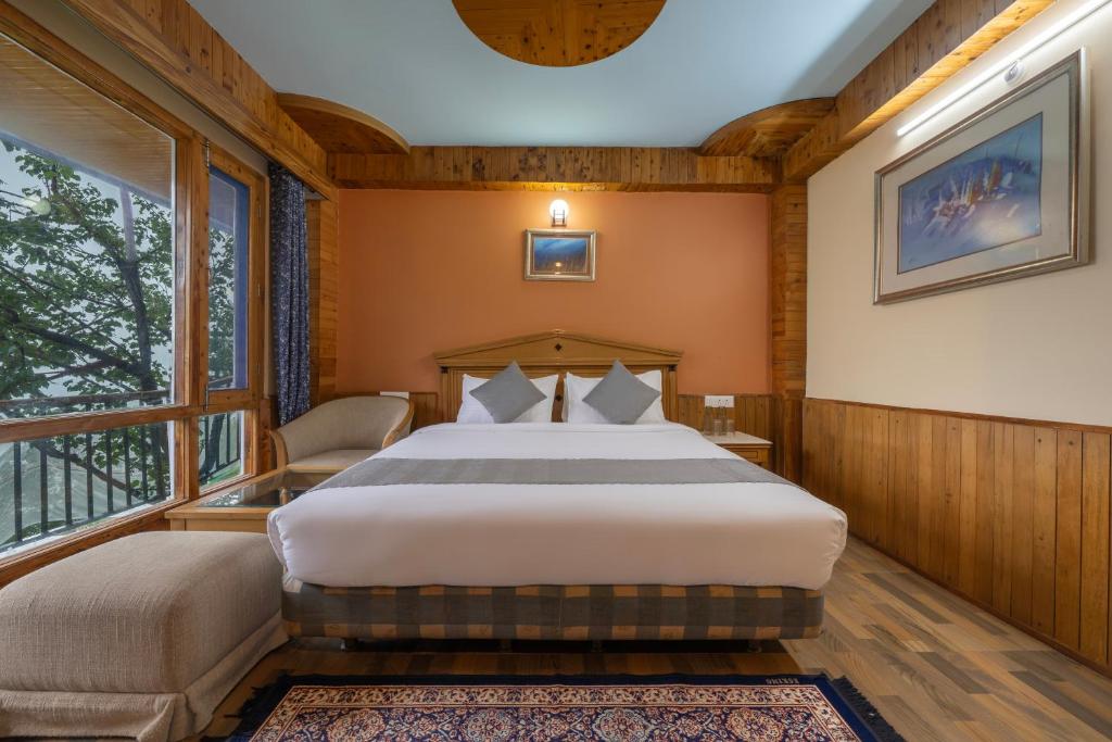 a bedroom with a bed and a large window at Splendid Retreat Hotels Kufri in Kūfrī
