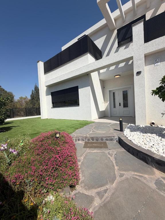 a white house with a pink bush in front of it at וילה יובל in Yuval