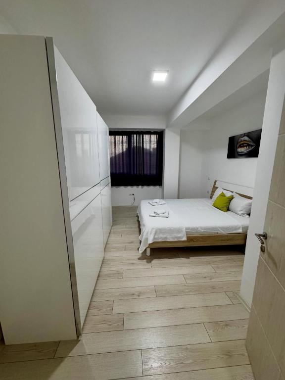 a white bedroom with a bed and a window at Neptun Apartments in Gevgelija