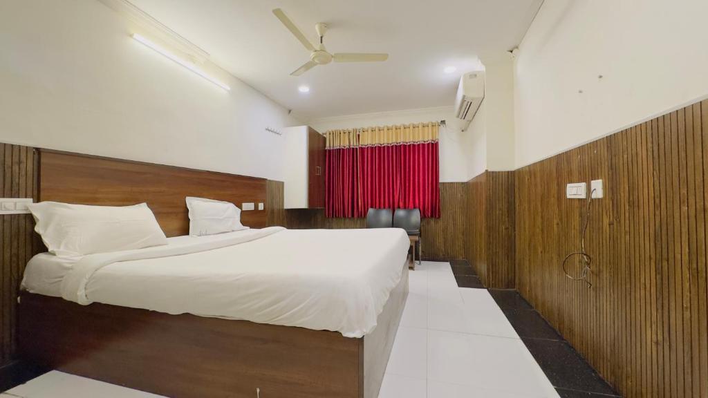 a bedroom with a large bed and a red curtain at Tirupati Stays in Tirupati