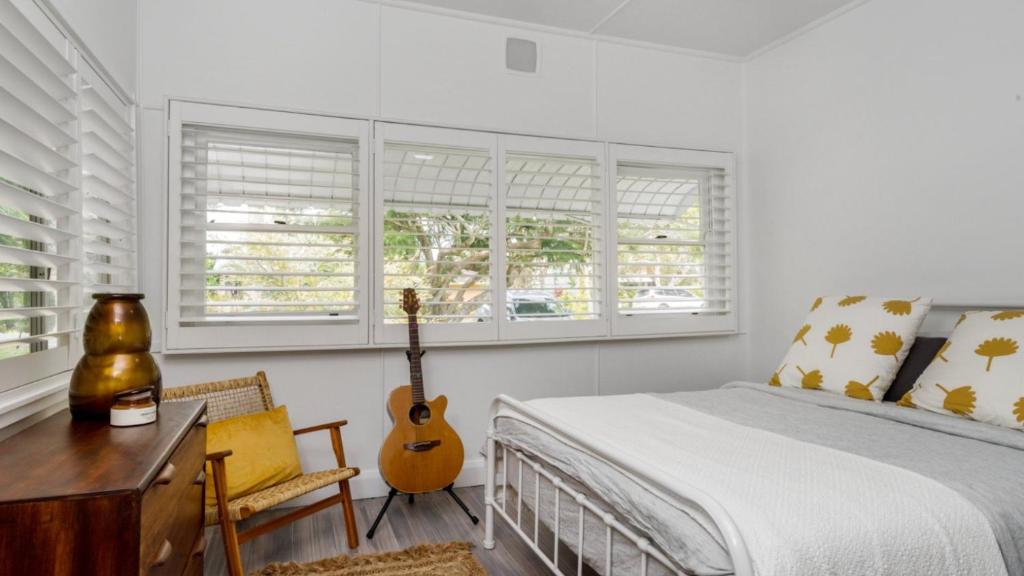 a bedroom with a guitar and a bed with a desk at Bruns Beach Shack in Brunswick Heads