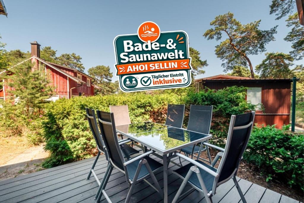 a table and chairs on a deck with a sign at Ferienhaus am Strand 88 - Bade- & Saunawelt täglich inklusive in Baabe