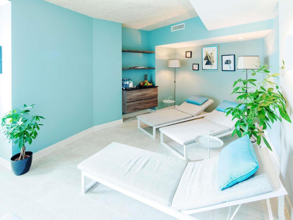 a living room with two white benches and blue walls at Grand Hotel Bregenz - MGallery Collection in Bregenz