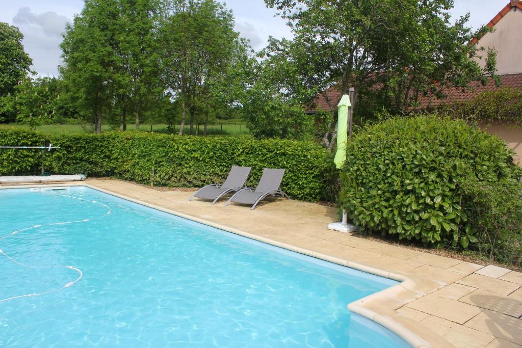 a swimming pool with two chairs and an umbrella at Petit Crecy 