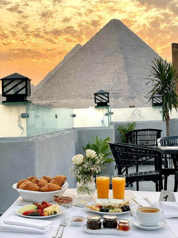 a table with food and a pyramid in the background at Miami Pyramids View in Cairo