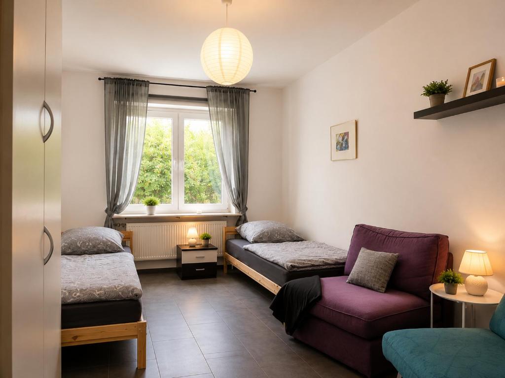 a room with two beds and a couch and a window at Apartments am Heimbach EG rechts in Kassel