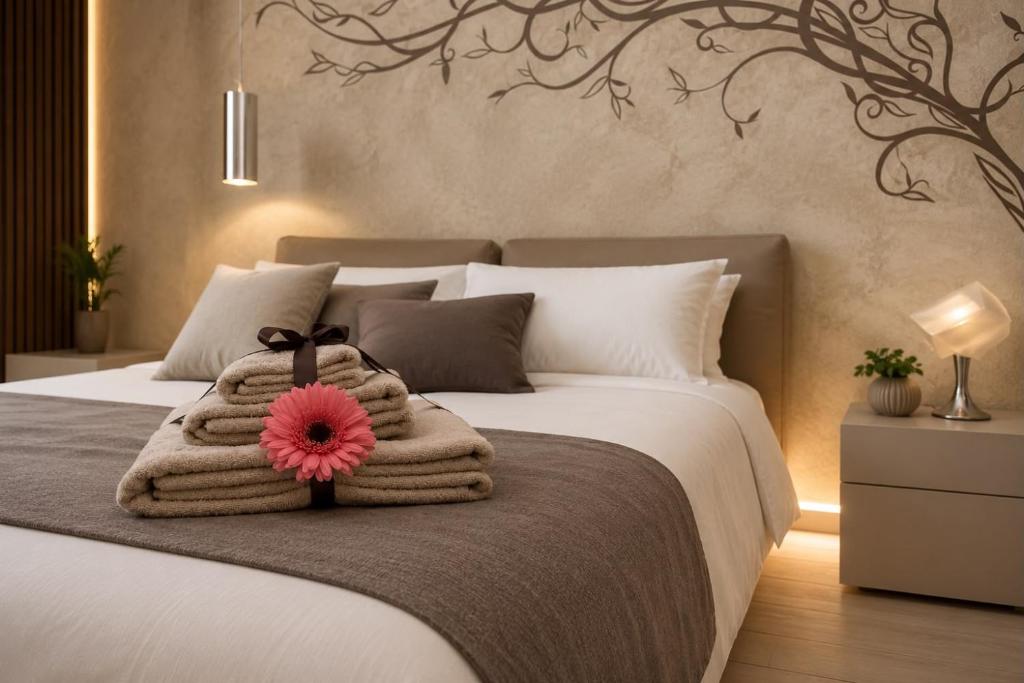 a bed with a blanket and a pink flower on it at OLYMPUS PARK amnesia in Mesagne