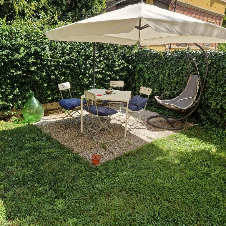 a table and chairs under an umbrella in the grass at Minimal Chic Apartment Garden Free Parking Bologna 5 Min to Center in Bologna