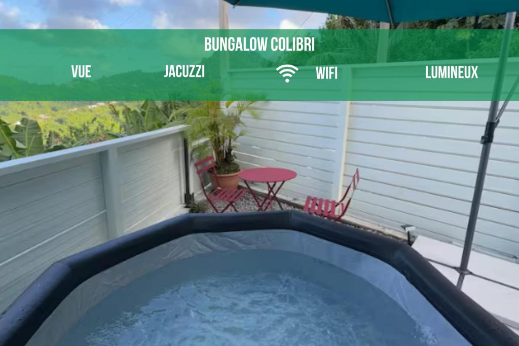 a hot tub on a balcony with a table and chairs at Studio Colibri vue mer in Quartier Morne Acajou