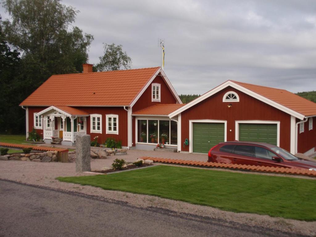 a red house with a car parked in front of it at Sjöanäs 3 in Tolg