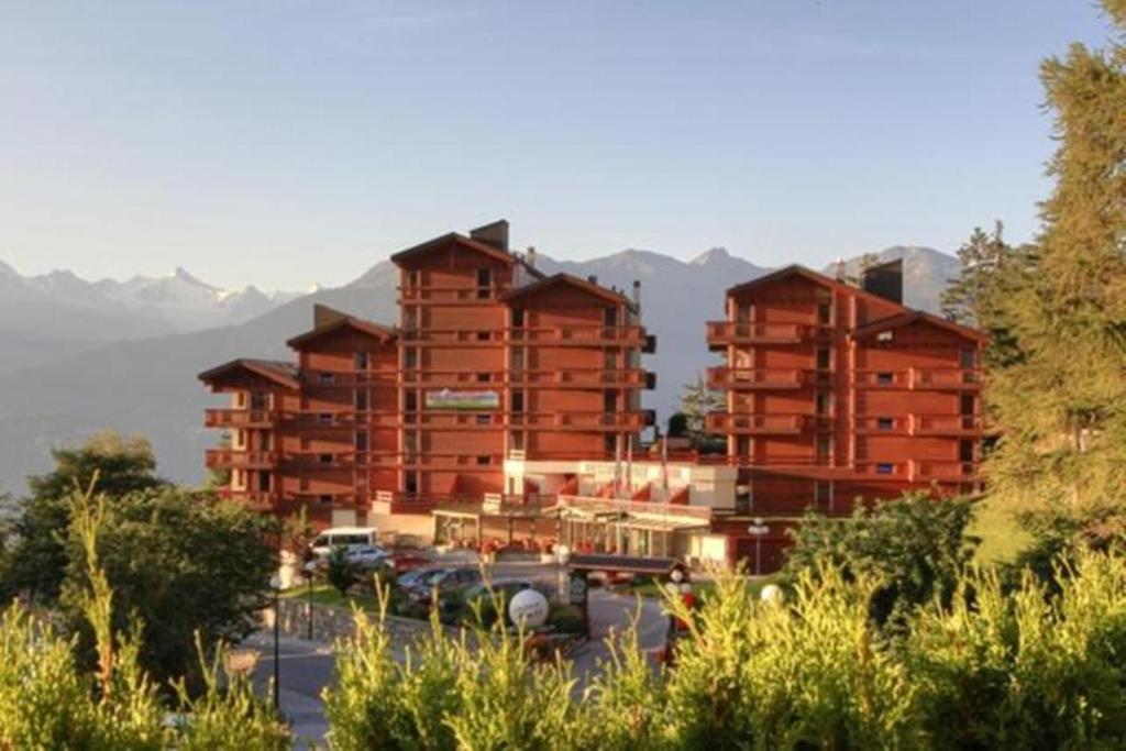 a large building with cars parked in a parking lot at Aparthotel Helvetia in Crans-Montana