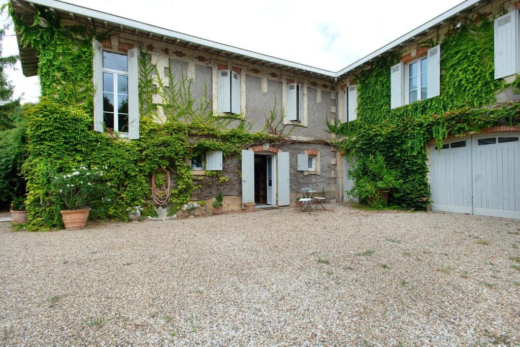 an ivy covered house with a gravel driveway at B&B L'Annexe De Camillac in Bourg-sur-Gironde