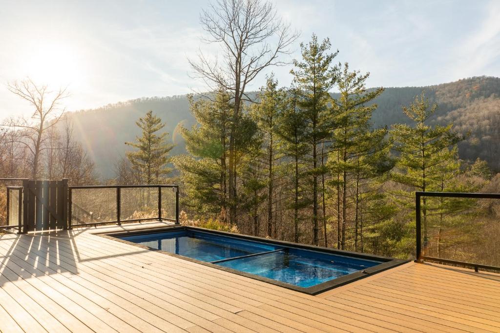 a hot tub on a deck with a view of the mountains at Fawn Hill Elevated Log Cabin w Year-Round Pool in Phoenicia