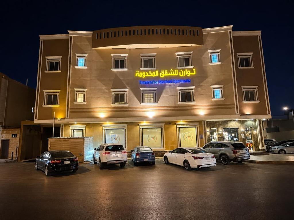 a large building with cars parked in a parking lot at توارن للشقق المخدومة - الاقتصادية in Riyadh