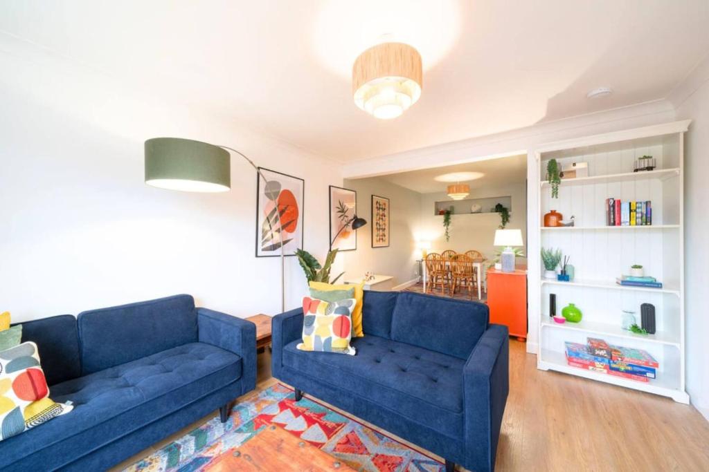 a living room with two blue couches and a kitchen at Westland Shores - An East Neuk Gem in Crail
