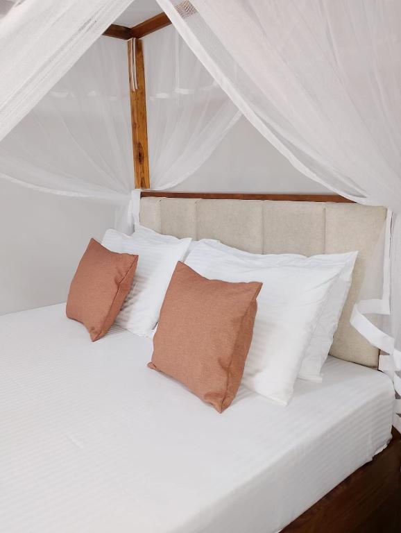 a bed with white pillows and a white canopy at The White Porch in Kurunegala