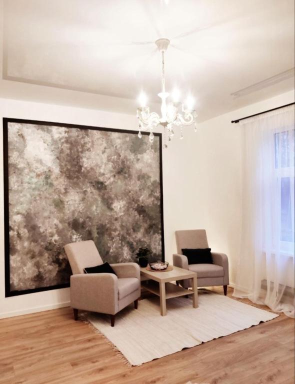 a living room with two chairs and a table and a painting at Muna Living in Riga