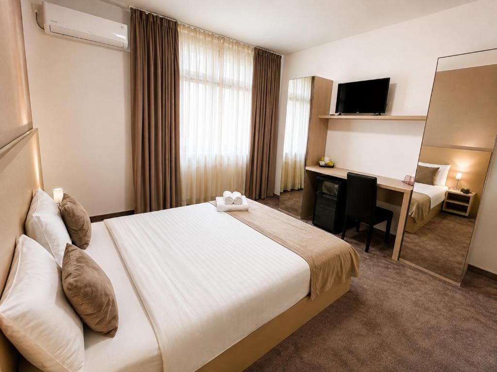 ein Hotelzimmer mit Bett und Schreibtisch in der Unterkunft Hotel Rivoli in Bukarest