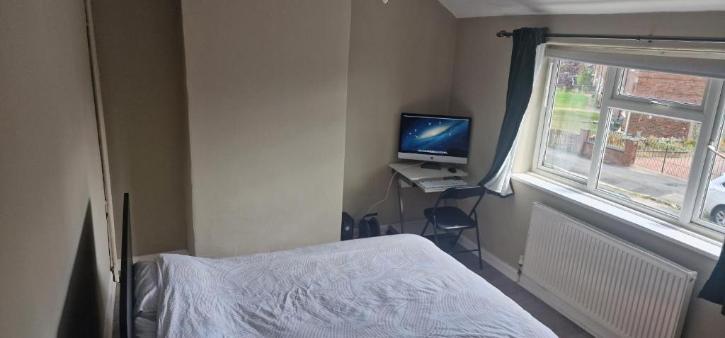 a bedroom with a bed and a computer monitor and a window at 4 Boteler Avenue,Bewsey in Warrington