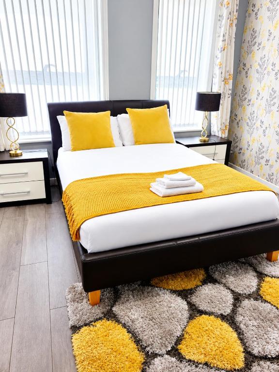 a bedroom with a bed with yellow pillows and a rug at B&G Homes in Hollinwood