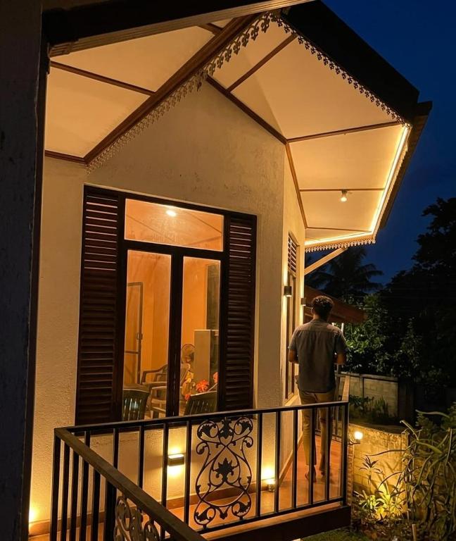 a man standing on the balcony of a house at night at Freedom Rest Rooms in Anuradhapura