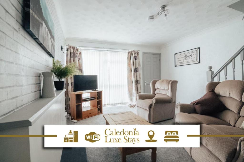 a living room with a couch a chair and a television at Dinorben Retreat in Amlwch