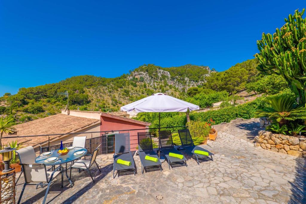 eine Terrasse mit Tisch, Stühlen und Sonnenschirm in der Unterkunft Cal Tio in Caimari