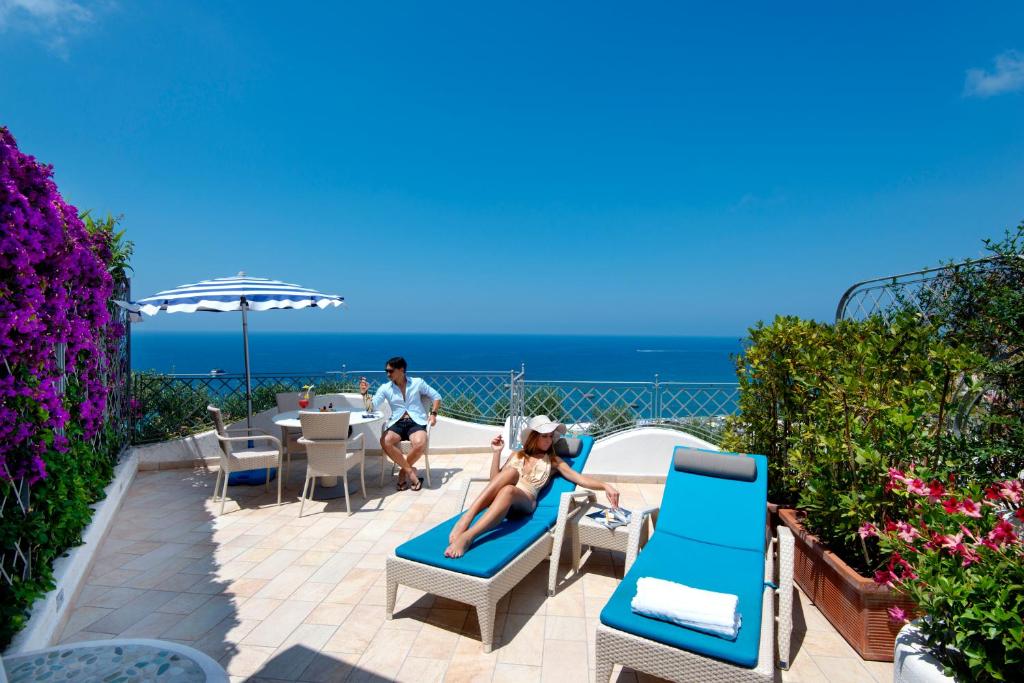 a woman laying on a chair on a patio overlooking the ocean at Sorriso Thermae Resort & Spa in Ischia