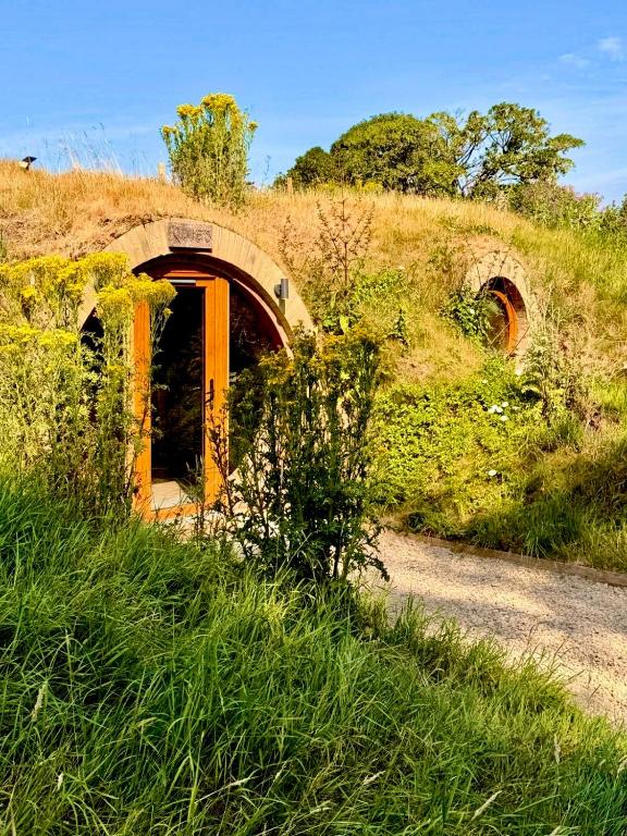 an old building on a hill with grass at Arts Hollow in Binegar