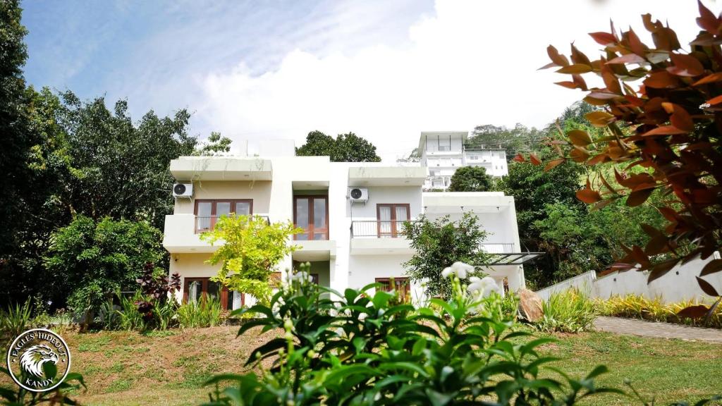 a white house on a hill with trees at Eagles Hideout Kandy in Bowala