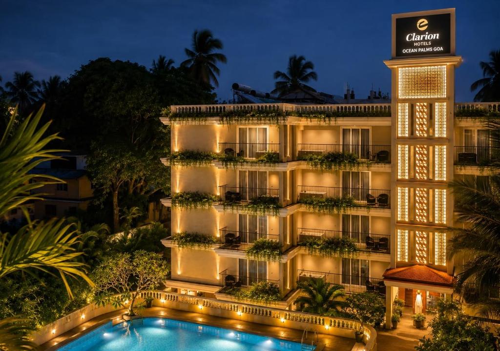 a hotel with a swimming pool at night at Clarion Hotel Ocean Palms Goa in Calangute