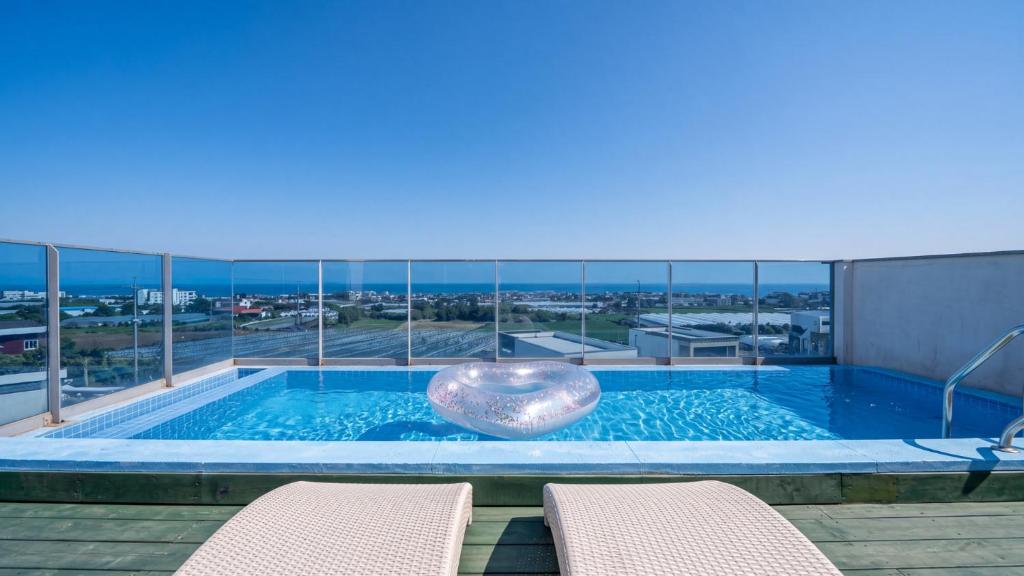 a swimming pool on the roof of a building with chairs at Seogwipo Dawa Pool Villa Pension in Seogwipo