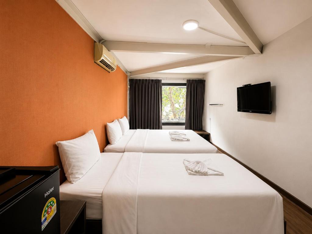 a hotel room with two beds and a television at SaintLove Hotel in Chiang Mai