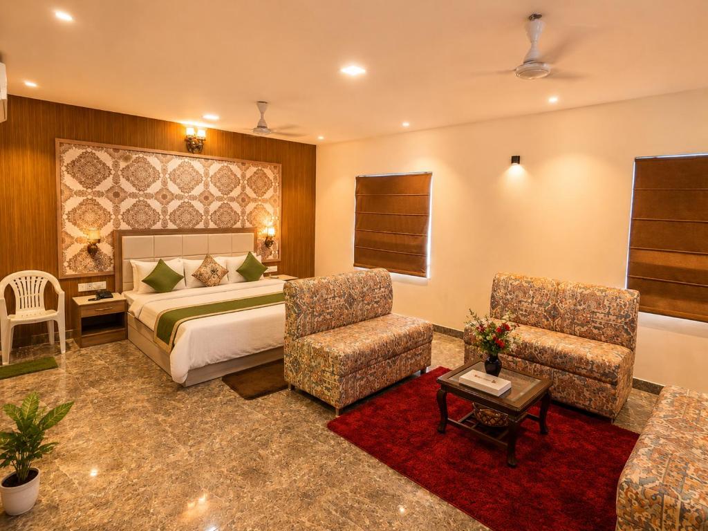 a hotel room with a bed and two chairs at HOTEL LUXURY KASHI VISHWANATH- VARANASi in Varanasi