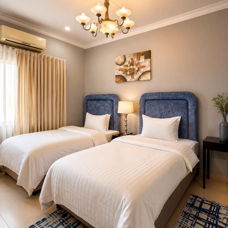 a bedroom with two beds and a chandelier at moon havena مون هافينا in Dhahran