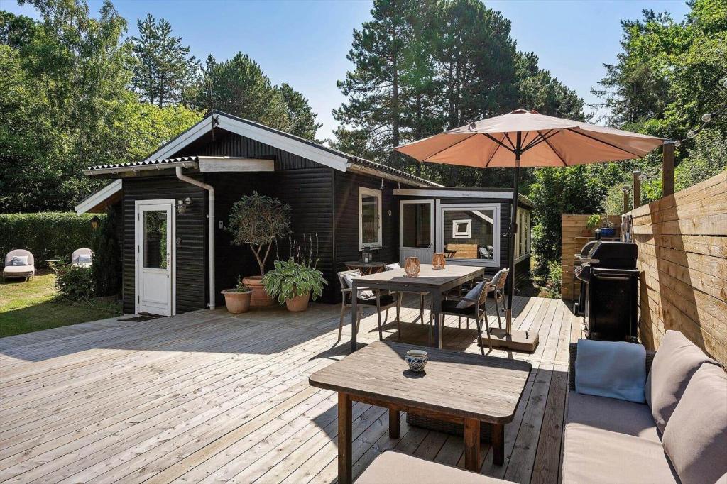 a wooden deck with a table and an umbrella at FJ1404-Jaegerspris-Strandstien-17 in Jægerspris