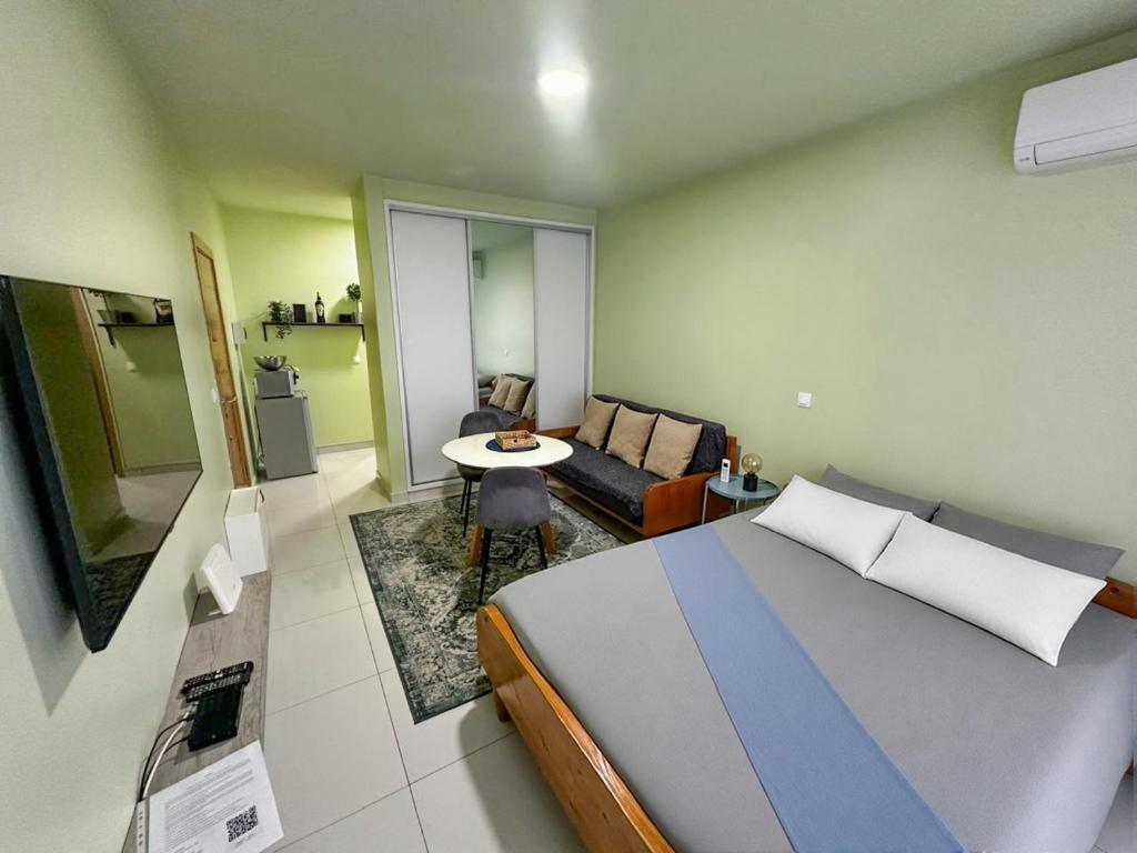 a bedroom with a bed and a living room at AP2B Praia in Praia