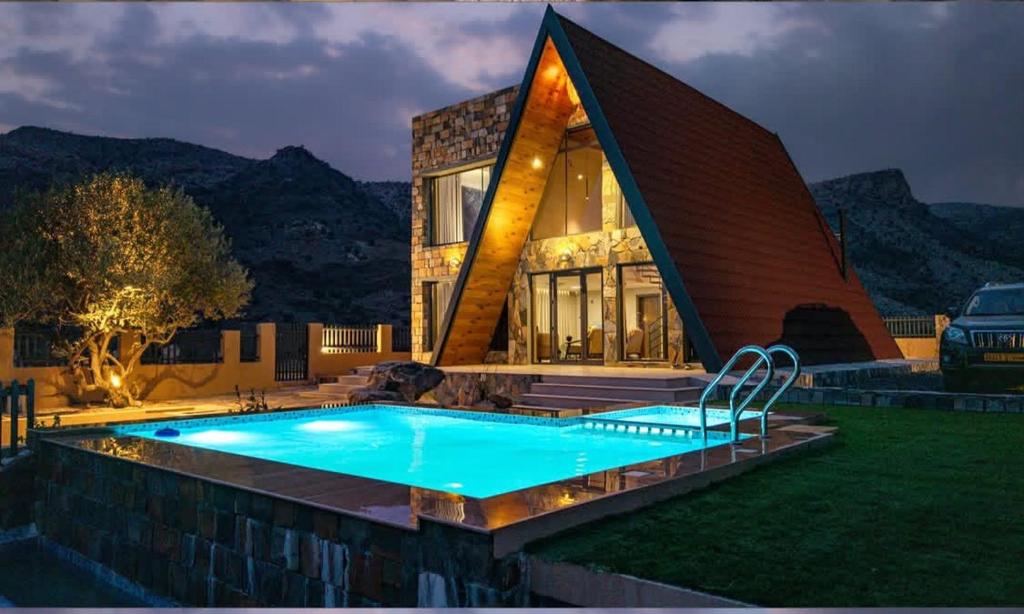 a house with a swimming pool in front of a house at Apex Hills تلال القمة in Dār Sawdāʼ