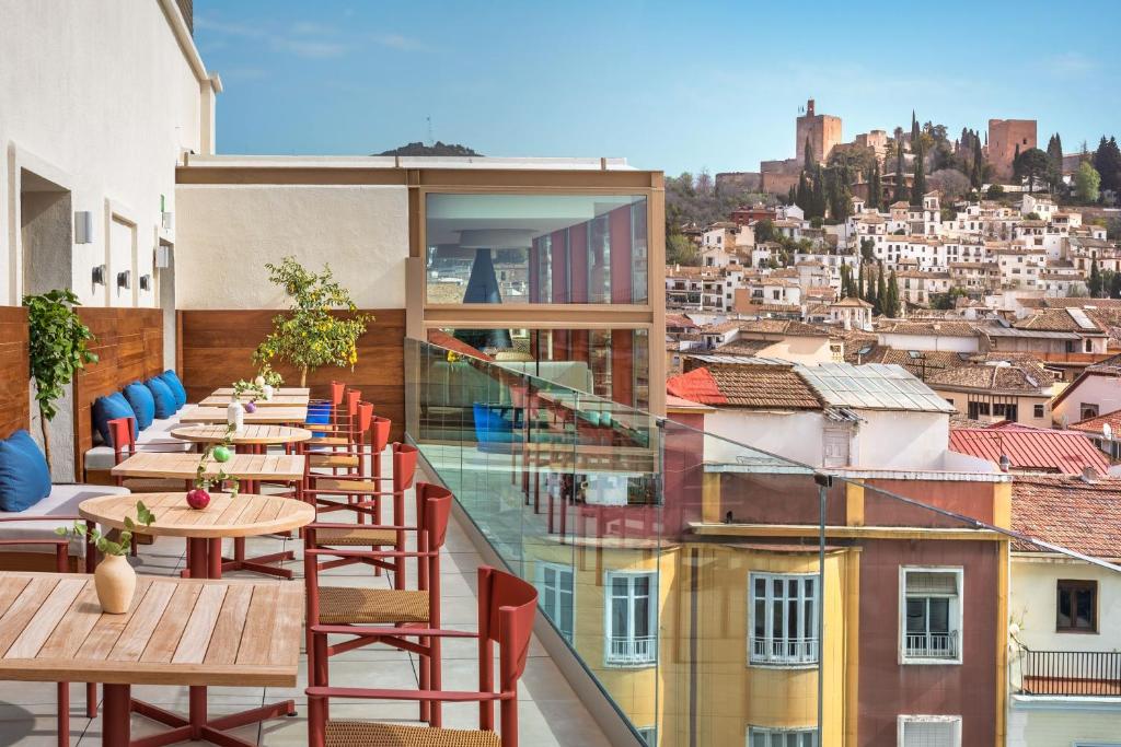 ein Balkon mit Tischen und Stühlen und eine Stadt in der Unterkunft Meliá Granada in Granada