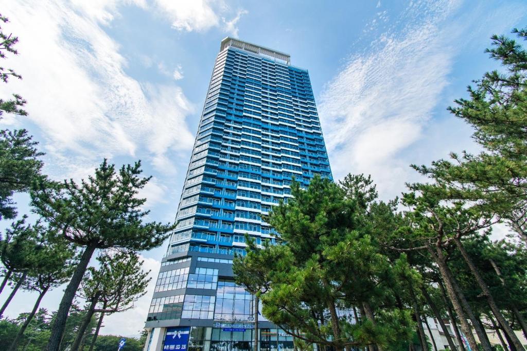a tall glass building with trees in front of it at 플럼바고올스위트1809 in Sangun-ni