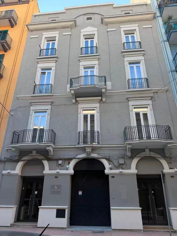 a large gray building with balconies on a street at Leonida Residence in Taranto